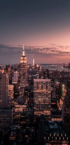 the city skyline is lit up at night, with skyscrapers in the foreground