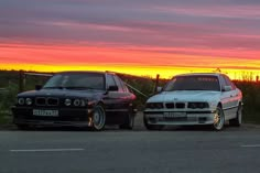 two cars parked next to each other in front of a sunset