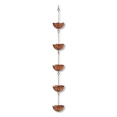 three tiered glass bowl hanging from a metal chain on a white wall in front of a