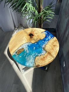 a wooden table with blue paint on it and a potted plant in the corner