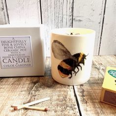 a candle with a bee on it next to some matches and a box of matches