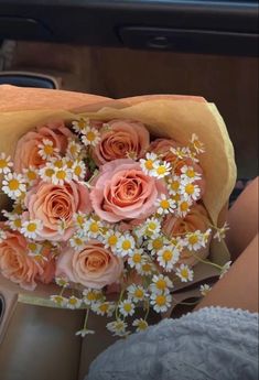 a bouquet of daisies and roses in a woman's lap