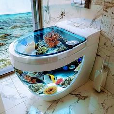 a toilet with an aquarium on the lid in a bathroom next to a window overlooking the ocean