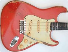 an old red electric guitar is hanging on the wall