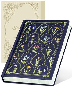 an open book with embroidered flowers on the front and back cover, next to a card