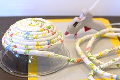 there is a cord that has been wrapped around the top of a glass bowl on a yellow and white table cloth