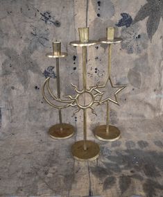 two brass candlesticks sitting on top of each other in front of a wall