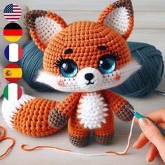 a crocheted fox is sitting next to a ball of yarn and knitting needles