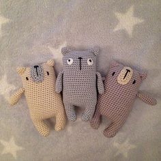 three crocheted teddy bears laying on top of a white bed covered in stars