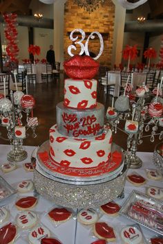 a red and white wedding cake with the number twenty on top is surrounded by desserts