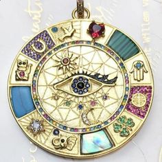 a gold pendant with an all seeing eye on it's center and colorful stones in the middle