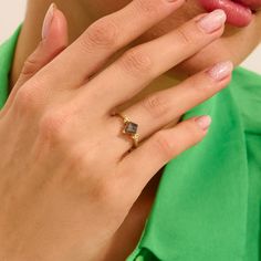 a close up of a person with a ring on their finger and wearing a green shirt