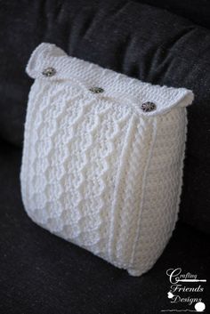 a white knitted bag sitting on top of a black couch