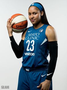 a woman holding a basketball in her right hand and wearing a headband on the other