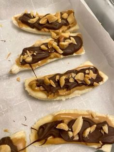 chocolate covered pretzels sitting on top of a piece of wax paper with nuts