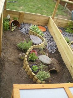 an outdoor garden with rocks, plants and gravel on the ground next to a wooden fence