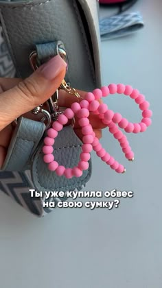 a hand holding a key chain with pink beads