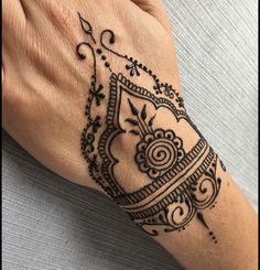 a woman's hand with a henna tattoo on her arm and wrist,