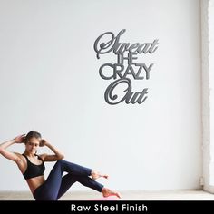 a woman sitting on the floor in front of a wall that says sweat it crazy out