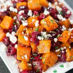 a white plate topped with sweet potatoes, cranberries and parmesan cheese