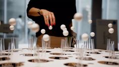 a woman standing in front of a table filled with wine glasses and white balls on it