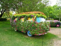 an old vw bus covered in flowers and plants