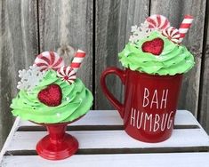 two red mugs with green frosting and candy canes