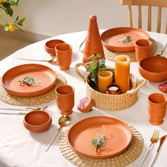 the table is set with orange plates and utensils