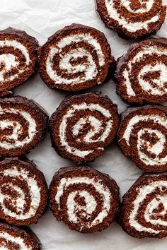 there are many chocolate rolls with white frosting on them