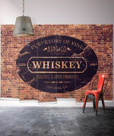 a red chair sitting in front of a brick wall with a sign that says whiskey on it