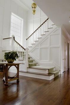 an entryway with stairs and potted plant on the table in front of it