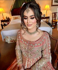 a woman sitting on top of a wooden table wearing a dress and headpieces