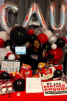 a woman sitting at a table with balloons and signs