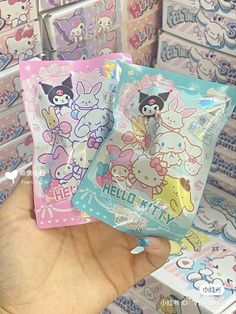 the hand is holding two packets of hello kitty gums in front of many boxes