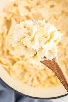 a wooden spoon full of mashed potatoes in a white pot with a blue cloth