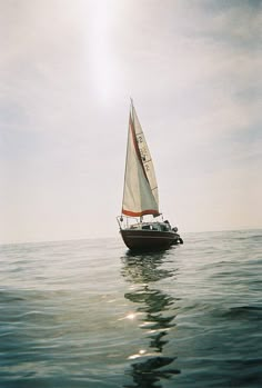 a sailboat floating in the ocean on a sunny day