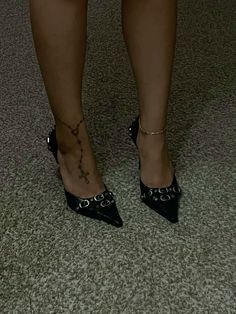 a woman's legs wearing black shoes with chains on the ankles and ankle tattoos