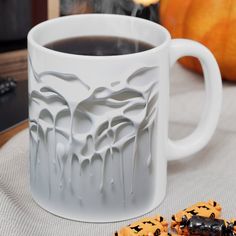 a cup of coffee and some cookies on a table with pumpkins in the background