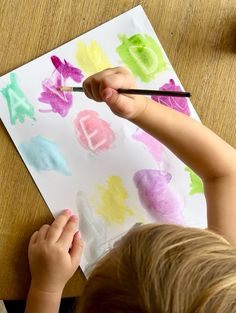 a young child is painting with watercolors on paper