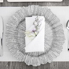 a place setting with silverware, napkins and flowers on the plate cover is shown