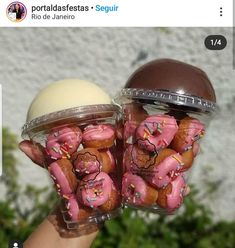 two plastic containers filled with pink frosted donuts in front of a white wall