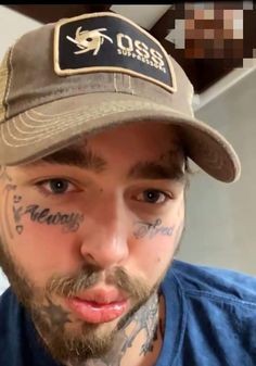 a man with tattoos on his face wearing a hat and looking at the camera while taking a selfie