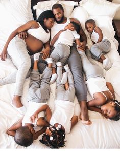 a group of people laying on top of each other in the middle of a bed