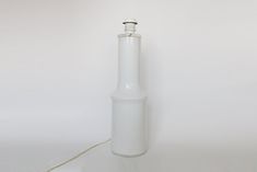 a white glass bottle with a cord attached to the end is shown in front of a white background