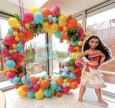 a barbie doll standing in front of a balloon arch