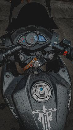 the handlebars and gauges on a motorcycle are covered in water droplets from rain