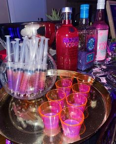 there are many cups and bottles on the table with pink liquids in each glass cup