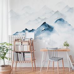 a desk and chair in front of a wall with mountains painted on it