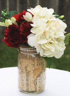 a vase filled with white and red flowers on top of a table next to a fence