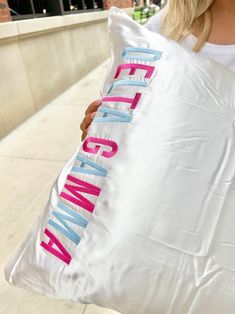 a woman holding a large pillow that says gettin'em up in pink and blue